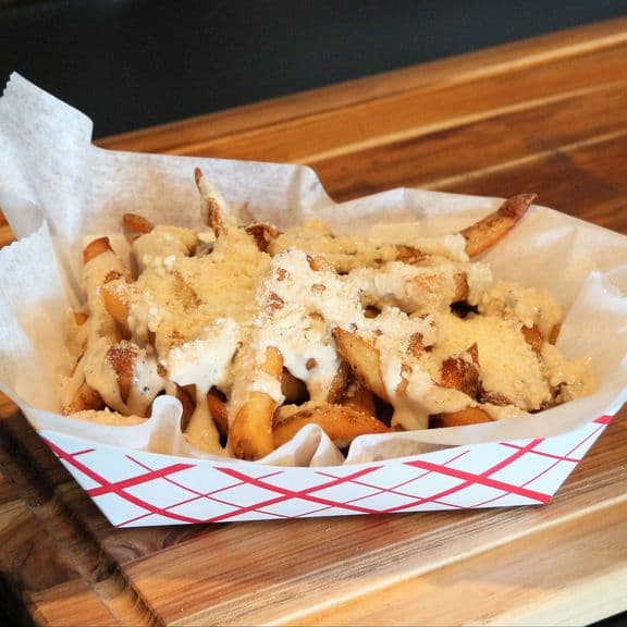 Caesar Fries - Crispy french fries drizzled with Caesar dressing and topped with freshly shaved Parmesan cheese. A unique Italian-inspired variation.