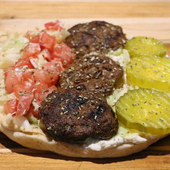 Kofta Pita Wrap - Special house marinated ground beef, fresh lettuce, tomato, pickles, hummus and tzatziki sauce, wrapped in warm pita bread.